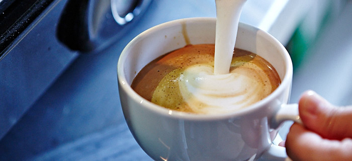 Milk being poured into a cup of coffee